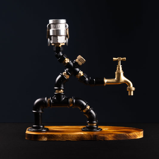 A rustic style liquor dispenser with a metallic brass body and a wooden base, featuring a single button on top for dispensing.